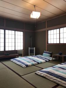 2 Betten in einem Zimmer mit 3 Fenstern in der Unterkunft Garden House Umenoya Otaru in Otaru