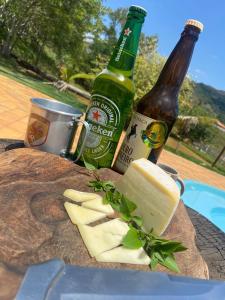 dos botellas de cerveza y queso en una mesa en Pousada Chales da Canastra, en Vargem Bonita