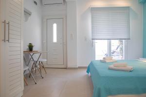 Schlafzimmer mit einem Bett mit blauer Bettwäsche und einem Fenster in der Unterkunft Central Apartments in Stavros