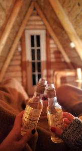a person holding two bottles of alcohol in front of a house at Cottage Uskoci in Žabljak