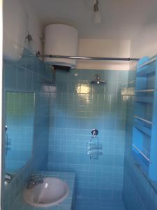 een badkamer met een wastafel en een blauwe tegelmuur bij Casa blu in Conca Specchiulla