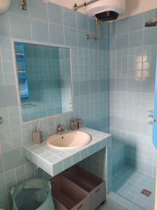 een blauw betegelde badkamer met een wastafel en een spiegel bij Casa blu in Conca Specchiulla