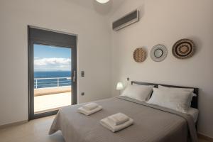 sypialnia z łóżkiem i widokiem na ocean w obiekcie Villa del Mare, built on the edge of the sea w mieście Chorafakia