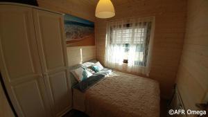 niewielka sypialnia z łóżkiem i oknem w obiekcie Domki Letniskowe Ratownik w Sarbinowie