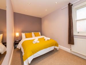 una camera da letto con un letto giallo e asciugamani di Pass the Keys Newly Renovated Stylish 2BR Flat in Town Centre a Reading