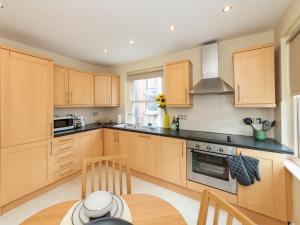a kitchen with wooden cabinets and a table in it at Pass the Keys Newly Renovated Stylish 2BR Flat in Town Centre in Reading
