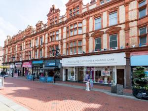 a street with a large brick building with stores at Pass the Keys Newly Renovated Stylish 2BR Flat in Town Centre in Reading