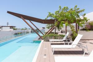 einen Pool auf dem Dach eines Gebäudes mit weißen Liegestühlen in der Unterkunft Stylish Condo - Private Plunge Pool - 300Mbps - Rooftop in Playa del Carmen