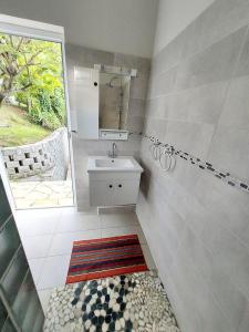 a bathroom with a sink and a mirror and a window at L' authentique in La Trinité