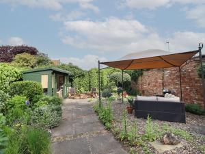 a patio with an umbrella in a garden at Hangmans cottage in Horncastle