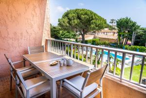 einen Tisch und Stühle auf einem Balkon mit Poolblick in der Unterkunft Eden Azur in Golfe-Juan