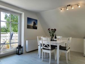 a white dining room with a white table and chairs at Ferienwohnung "Frau Böhl" in Sankt Peter-Ording