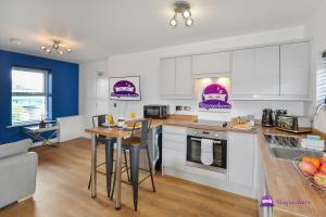 a kitchen with white cabinets and a table with chairs at Annie 1 bed Apartment next to rail station - STAYSEEKERS in Salisbury