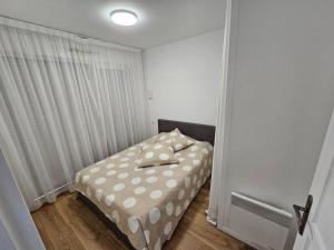 a small bedroom with a bed with polka dot sheets at T2 Saint Jean de Luz 200m plage in Saint-Jean-de-Luz
