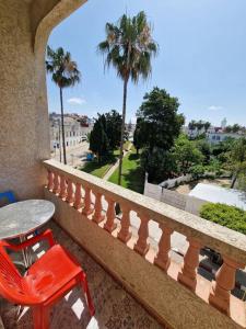 uma cadeira vermelha e uma mesa numa varanda em Large Family Apartment by Beach & center of town em Asilah