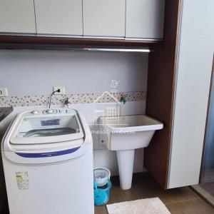 uma pequena cozinha com um lavatório e uma máquina de lavar roupa em Casa Jardim Itália II em Maringá