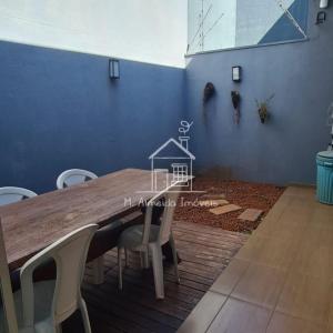 uma mesa de jantar com cadeiras e uma parede azul em Casa Jardim Itália II em Maringá