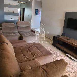 uma sala de estar com um sofá e uma televisão de ecrã plano em Casa Jardim Itália II em Maringá