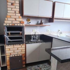 a kitchen with a stove top oven next to a brick wall at Casa Jardim Itália II in Maringá