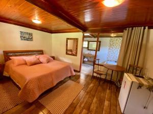Un dormitorio con una cama y una mesa. en Pousada Vale da Represa, en Visconde De Maua