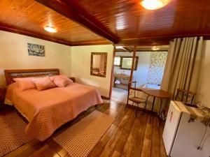 a bedroom with a bed and a table in it at Pousada Vale da Represa in Visconde De Maua