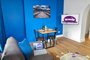 a living room with a table and a blue wall at Clarabel Studio Apartment - Stayseekers in Salisbury