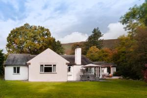 a white house on a green field with trees at Bellfoot Rural Retreat and Hot Tub in Grasmere