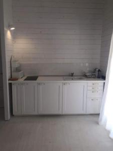 una cocina con armarios blancos y fregadero en Casa Blanca Olimp, en Olimp