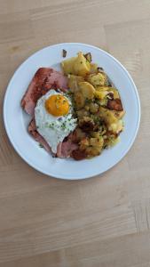 a plate of breakfast food with an egg and potatoes at Gasthof zum Lehnerwirt in Breitenbrunn