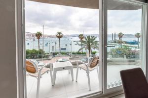 balcón con mesa, sillas y vistas al agua en Seafront Luxury Apartment en St. Paul's Bay