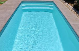 a blue swimming pool with a concrete border at Chalet Isla Papua in Chiclana de la Frontera