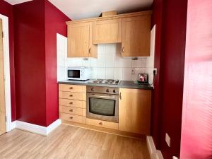 eine Küche mit Holzschränken und einem Herd mit Backofen in der Unterkunft Riverside Apartment at Woodsmill Quay in York