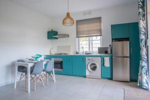 a kitchen with green cabinets and a table and chairs at Le Rivage Appartement Mauritius in La Gaulette