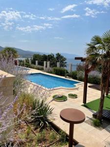 vistas a una piscina con una mesa al lado en Großzügiges Appartement direkt am Meer mit eigenem Pool - Povile Suites, en Novi Vinodolski