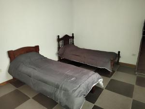2 camas en una habitación con suelo a cuadros en Complejo privado guaymallen en Guaymallén