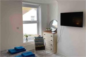 a living room with a television and a dresser with a mirror at Stunning seaside studio in Worthing