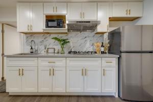 Una cocina con gabinetes blancos y un refrigerador de acero inoxidable. en Efficiently Equipped Pacifica Apt - 1 Mi to Beach!, en Pacífica