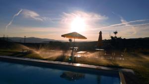 a swimming pool with an umbrella and the sun at Quinta do Outono in Armamar