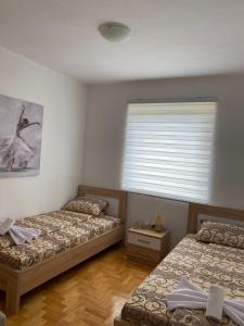 a bedroom with two beds and a window with a window blind at Apartment Varezić in Pluzine
