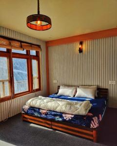 een slaapkamer met een bed in een kamer met ramen bij Grease Moto Club - Khangsar, Sissu in Sissu