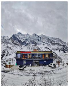 een gebouw voor een met sneeuw bedekte berg bij Grease Moto Club - Khangsar, Sissu in Sissu