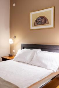 a bed with white sheets and a picture on the wall at Geo city center room in Athens