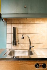 a kitchen sink with a faucet on a tiled wall at Geo city center room in Athens