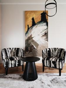 two chairs and a table in a room with a painting at Hoppen House Apartamenty w centrum miasta in Radom
