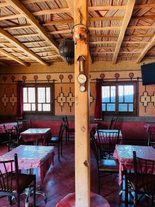 una sala da pranzo con tavoli, sedie e soffitti in legno di Kasbah Tialouite a El Kelaa des Mgouna