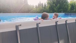 a boy and a girl in a swimming pool at Country house in Banja Luka