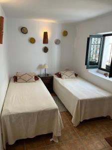 2 camas en una habitación con paredes y ventanas blancas en Casa idrisi en Albuñuelas