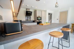 a kitchen with a large counter with two stools at Princes Close - Spacious Modern Luxury Home in Windsor