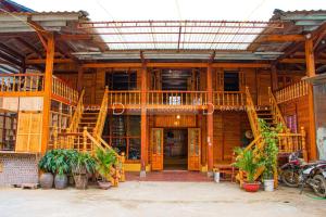 um grande edifício de madeira com escadas e vasos de plantas em A Phủ Home’s em Bắc Yên