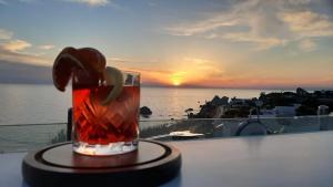 a drink on a table with the sunset in the background at Hotel Albatros in Ischia